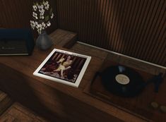 a record player, vase with flowers and an album sitting on a table in front of a wooden paneled wall