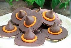 chocolate covered desserts with orange icing on a white plate next to green plants