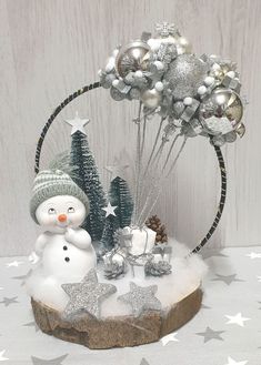 a snowman and christmas tree decoration with silver baubs on a white table cloth