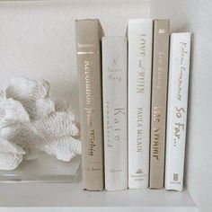 some books are sitting on a shelf next to a vase with white flowers in it