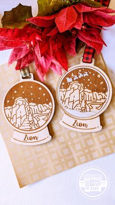 two wooden medals sitting on top of a piece of paper next to red flowers