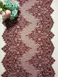 a lace table runner with pink flowers on it and a green flower in the middle