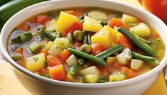 a white bowl filled with vegetable soup on top of a table