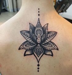 the back of a woman's neck with a tattoo design on it, and an intricate lotus flower