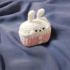 a small crocheted stuffed animal sitting on top of a blue cloth covered bed