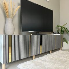 a flat screen tv sitting on top of a wooden cabinet next to a white rug