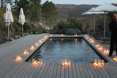 a man standing next to a pool filled with candles