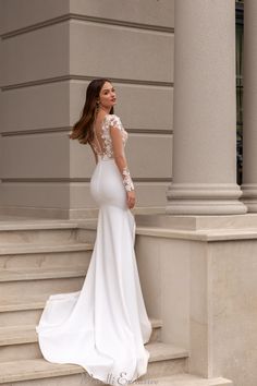 a woman in a white wedding dress standing on steps with her back to the camera