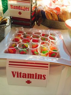 a bunch of cups that are sitting on a table with some food in the background