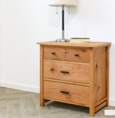 a wooden chest of drawers with a lamp on top