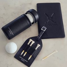 two golf tees and a ball on a marble table with a black leather case