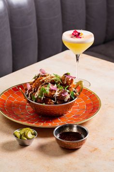 a bowl of food sitting on top of a table next to two bowls of dipping sauces