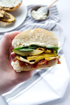 a hand holding a sandwich with meat and vegetables