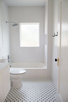 a white toilet sitting next to a bath tub in a bathroom with black and white tiles