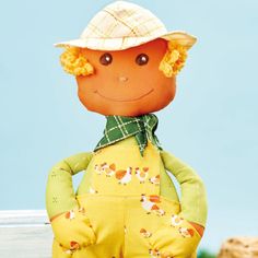 an orange doll with yellow overalls and a hat