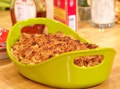 a green casserole dish filled with food on top of a wooden table