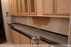 a kitchen with wooden cabinets and metal grate on the counter top in front of it