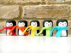 a row of penguin candles sitting on top of a white table next to a brick wall