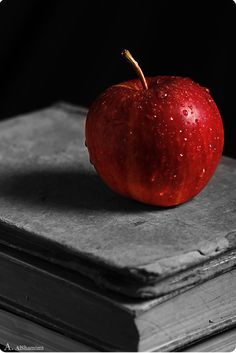 an apple sitting on top of a book with water droplets all over it's surface