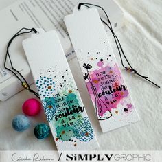 two bookmarks sitting on top of a table next to some beads and paper balls