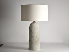 a white lamp sitting on top of a table next to a white wall and floor