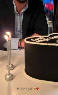 a man sitting in front of a cake with two candles