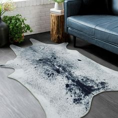 a living room with a blue couch and white cowhide rug on the floor next to a window