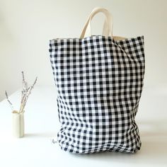 a black and white checkered tote bag next to a vase with lavenders