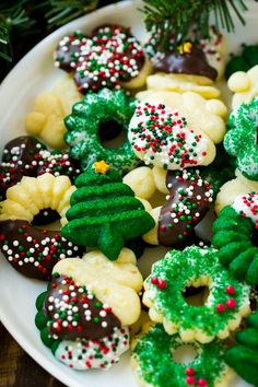 a white plate topped with lots of cookies covered in frosting and sprinkles