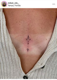 a woman's chest with a small cross tattoo on her left side ribcage