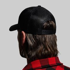 a man with long hair wearing a black and red plaid hat, looking at the back of his head