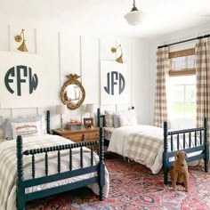 two twin beds in a white bedroom with blue frames and plaid bedding on the walls