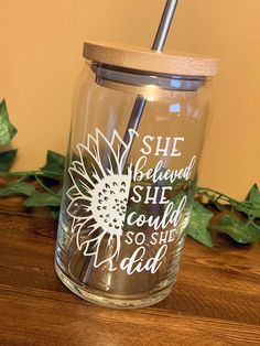 a glass jar with a straw in it sitting on a wooden table next to leaves