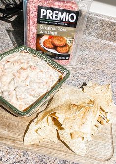 a bowl of shrimp dip next to some tortilla chips on a cutting board