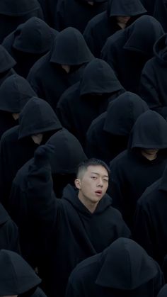 a group of men in black hoods standing together with their hands on their heads