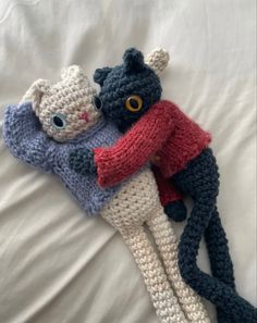 two crocheted stuffed animals laying on top of each other in the shape of cats