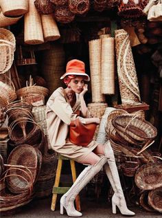 a woman sitting on a stool in front of baskets