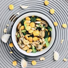 a white bowl filled with broccoli and chickpeas on top of a table