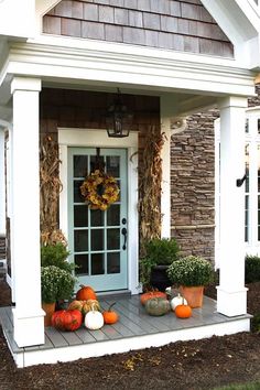 a front porch decorated for fall with pumpkins and gourds