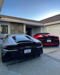 two supercars parked in front of a house on a driveway with the door open