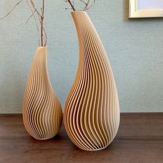 two wooden vases sitting on top of a table next to a plant in a vase