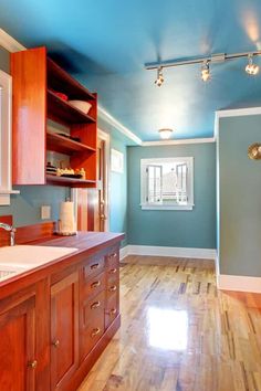 an empty kitchen with wood floors and blue walls