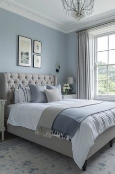 a bedroom with blue walls, white bedding and a chandelier hanging from the ceiling