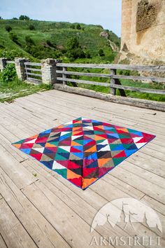 a multicolored patchwork rug sitting on top of a wooden deck