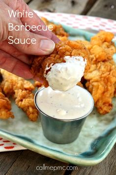 a person dipping sauce on chicken wings in a small bowl with the words white barbecue sauce above it