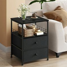 a white couch sitting next to a black end table with baskets on top of it