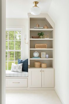 an empty room with white shelves and blue pillows