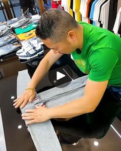 a man in a green shirt is working on a piece of furniture at a clothing store