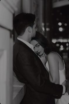 a man and woman embracing each other in black and white