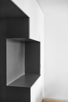 a black shelf sitting on top of a wooden floor next to a white wall in a room